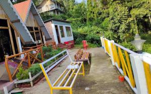 a group of chairs sitting on a patio with a house at Amar Bari Happy Valley Cottages by StayApart in Mangpu