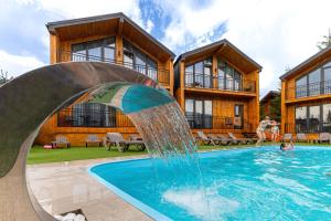 una piscina con scivolo d'acqua di fronte a una casa di Hotel Pid Strihoju a Bukovel