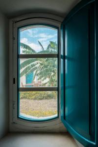 a window with a view of a palm tree through it at B&B Fermata 106 da Carolina in Siculiana Marina