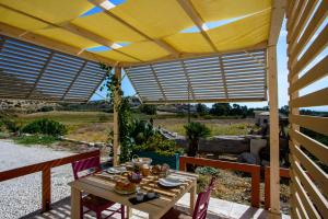a table and chairs under a yellow umbrella on a patio at B&B Fermata 106 da Carolina in Siculiana Marina