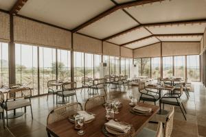 a restaurant with tables and chairs and windows at Teela- The Glamping Resort, Jaipur in Jaipur