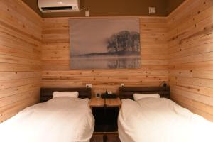 two beds in a room with wooden walls at アングラーズベース下北山 in Kami-ikehara