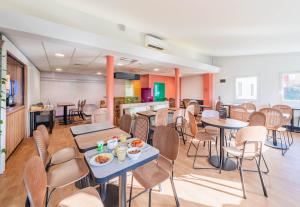 a dining room with tables and chairs and a fireplace at B&B HOTEL Strasbourg Nord Mundolsheim in Mundolsheim
