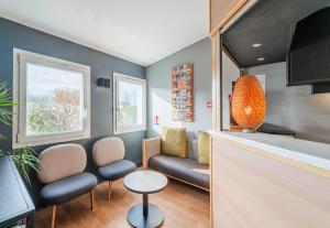 a living room with a couch and a table at B&B HOTEL Strasbourg Nord Mundolsheim in Mundolsheim