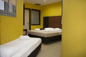 2 łóżka w pokoju z żółtymi ścianami w obiekcie INOH HOTEL w Atenach