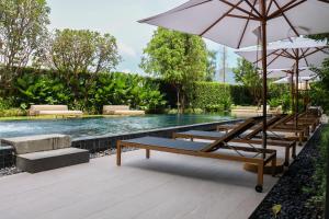 a pool with lounge chairs and an umbrella and a swimming pool at Lakeside Residences by NLA in Bang Tao Beach