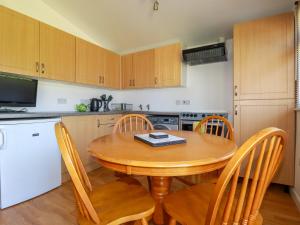 a small kitchen with a wooden table and chairs at Cornish Holiday at Atlantic Bays in Saint Merryn +5 photos