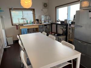 a kitchen with a table and chairs and a refrigerator at Otaru Eminabackpackers in Otaru