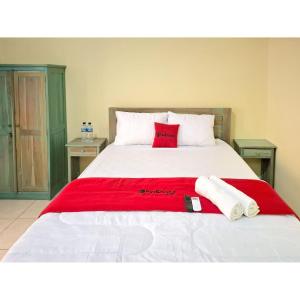 a bed with two red pillows and towels on it at RedDoorz near Alun Alun Jepara in Kesembu