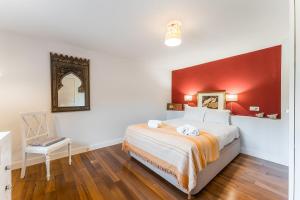 a bedroom with a bed with a red wall at GuestReady - Quintinha casas do jardim 2 in Arcos de Valdevez