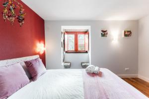a bedroom with a white bed and a red wall at GuestReady - Quintinha casas do jardim 2 in Arcos de Valdevez +94 photos