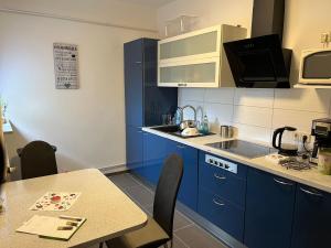 a small kitchen with blue cabinets and a table at Pension Gasthaus Schützenhaus in Waldenburg