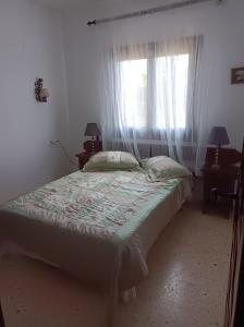 Un dormitorio con una cama y una ventana con cortinas. en Spanien Bungalow, en Teulada