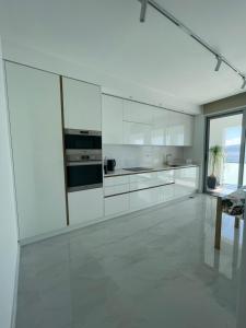 a white kitchen with white cabinets and a table at Suites Avenue Azores in Horta +27 photos