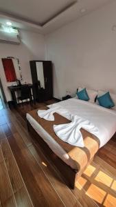 a bedroom with a large white bed with blue pillows at Hotel Bellagio Baga LLP in Arpora +4 photos