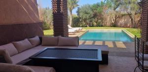 a living room with a couch and a swimming pool at Villa des oliviers in Marrakech