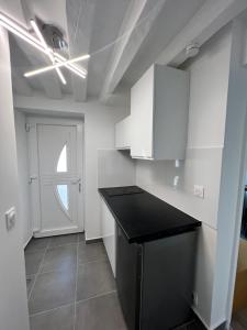 a kitchen with white cabinets and a black counter top at Studio Cozy proche aéroport CDG in Claye-Souilly