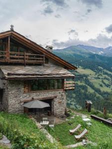 a house on a hill with chairs and an umbrella at Chez'Alma in Pragelato