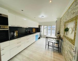a kitchen with white cabinets and a table in it at Maison Familiale avec Jardin in Ozoir-la-Ferrière