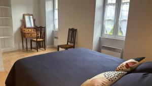 una camera da letto con un letto, uno specchio e una sedia di Gîte au cœur de la ville ancienne a Terrasson-Lavilledieu