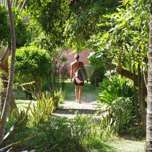 a woman walking down a path with a surfboard at Owa Lodge Areguling in Kuta Lombok