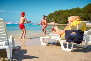 a woman sitting in a chair on the beach at Pine Beach Mobile homes all inclusive in Pakoštane +91 photos