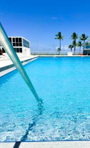 a swimming pool with blue water and palm trees at Castle 1029 Balcony studio with Ocean View, Pool, Tennis and Free Parking in Miami Beach