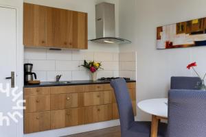 a kitchen with a sink and a table with blue chairs at OV593 - 4P apartment in the heart of Giethoorn on the village canal in Giethoorn