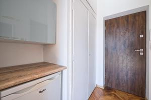 a kitchen with white cabinets and a wooden door at Urbannestgroup - City view N8 in Warsaw +5 photos