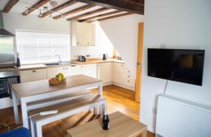 eine Küche mit einem Tisch und einem TV an der Wand in der Unterkunft Applecott - 2 bedroom Thatched cottage close to Stonehenge in Upavon