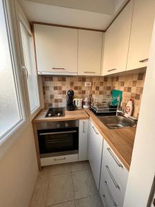 a small kitchen with white cabinets and a sink at Apartment City in Tivat +4 photos