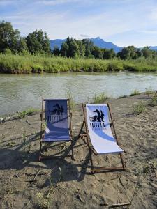 two chairs sitting on a beach next to a river at Hotel Fuchs & Hase SELF CHECK IN in Rosegg