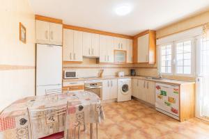 Una cocina con gabinetes blancos y una mesa en ella. en Finca Los Nieto, en Villamanrique de Tajo