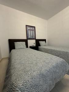 ein Schlafzimmer mit zwei Betten und einem Bild an der Wand in der Unterkunft Nazaret Home in Nazaret