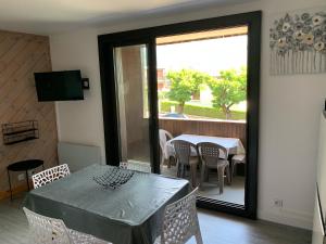 ein Esszimmer mit einem Tisch und Stühlen sowie einem Balkon in der Unterkunft Appartement agréable à deux pas du plan d'eau in Embrun