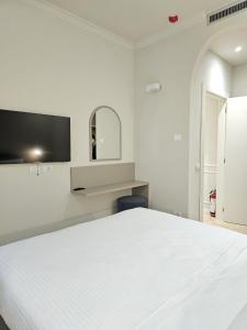 a white bedroom with a white bed and a tv at Andreola Central Hotel in Milan