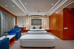 a hotel room with two beds and blue chairs at HOTEL SHITAL INN in Ahmedabad