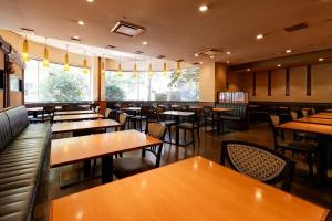 a restaurant with wooden tables and chairs and windows at Kurume Washington Hotel Plaza in Kurume