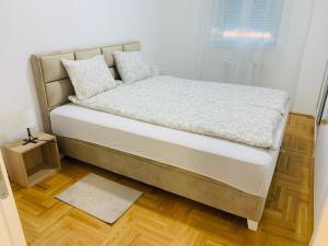 a bed with white sheets and pillows in a bedroom at Apartman Hana2 in Sombor