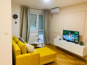 a living room with a yellow couch and a tv at Apartman Hana2 in Sombor