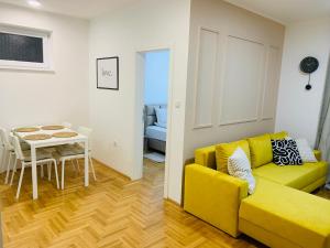 un soggiorno con un divano giallo e un tavolo di Apartman Hana2 a Sombor