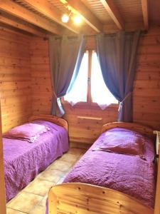 two beds in a log cabin with a window at Le gite du gabelou in Hargnies