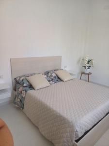 un letto in una camera da letto con parete bianca di "Nonna Maria" a Venegono Superiore