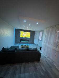 a living room with a couch and a flat screen tv at Très beau logement chic & cosy in Bonneuil-sur-Marne