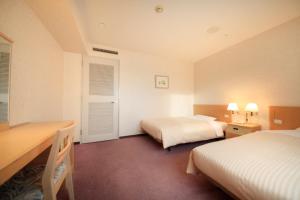 a hotel room with two beds and a desk at Kofu Washington Hotel Plaza in Kofu
