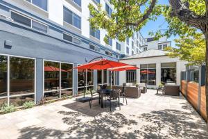 a patio with a table with an umbrella and chairs at Hilton Garden Inn San Mateo in San Mateo