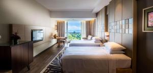 a hotel room with two beds and a television at DoubleTree Resort by Hilton Hotel Penang in Batu Ferringhi