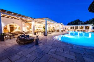 an outdoor patio with a swimming pool at night at Anthea Hotel in Tinos Town