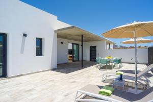Un patio con una mesa y sillas y una sombrilla. en Ereza Villas Artenara, en Playa Blanca