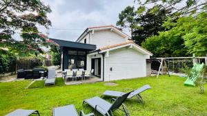 a backyard with chairs and tables and a house at Maison d'architecte de la Parée in Saint-Jean-de-Monts